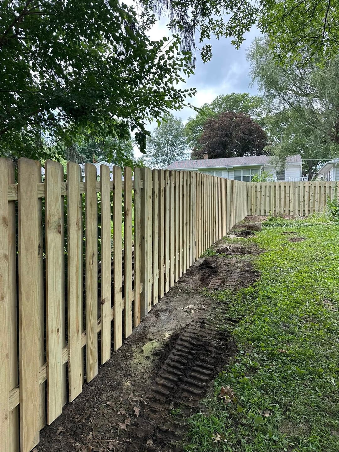 New wooden fence installation alongside a grassy area with clear blue skies in the background.