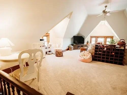 Cozy attic space with white decor, natural light, and wine rack for stylish storage.