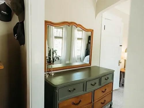 Vintage dresser with a large mirror in softly lit bedroom, enhancing the cozy atmosphere.