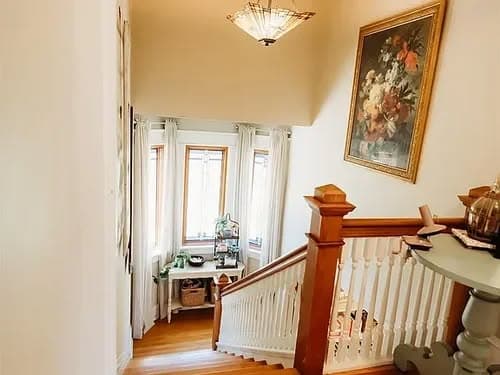 Bright staircase leading to a well-lit landing with floral artwork and decorative accents.