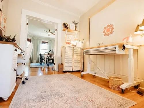 Home office with a desk, rolling table, and light-colored decor, featuring a woven basket.