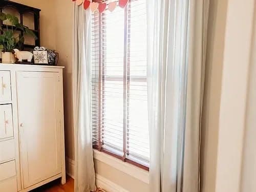 Bright living room corner with sheer curtains, a wooden window, and stylish decor.