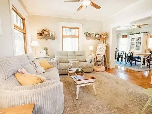 Cozy living room with striped sofas, hardwood floors, and a dining area in natural light.