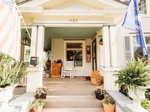 Charming front porch of a home with rocking chair, flags, and potted plants at 1022.