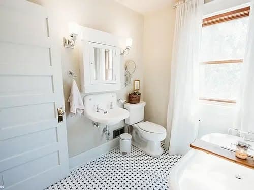 Modern bathroom with white fixtures, tiled floor, and natural light from a window.