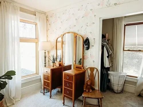 Cozy bedroom corner with vintage mirror, wooden furniture, and soft lighting.