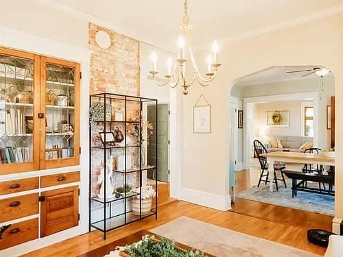 Warm, inviting living area with vintage furniture, chandelier, and decorative wooden shelving.