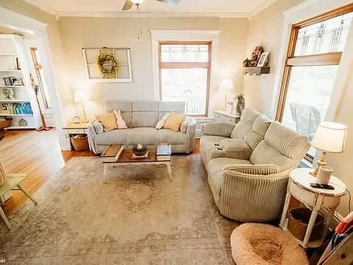 Cozy living room with light-colored furniture, large windows, and welcoming decor.