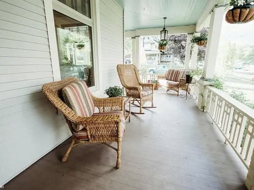 Cozy porch with wicker chairs, potted plants, and a welcoming atmosphere for relaxation.