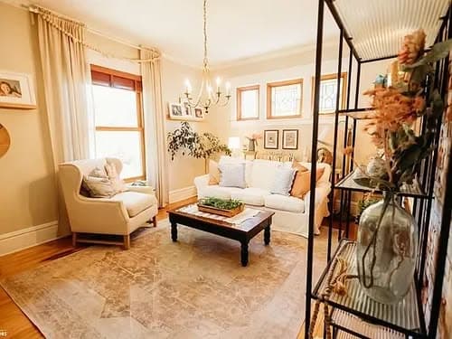 Cozy living room with a chandelier, plush seating, and decorative plants in natural light.