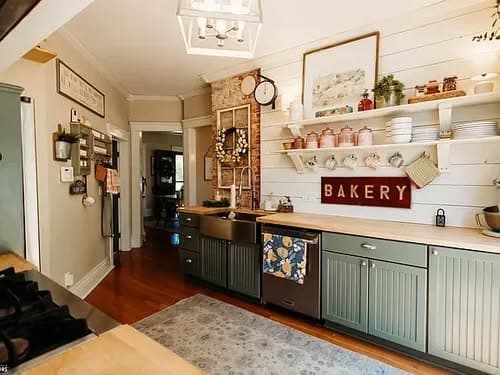 Cozy kitchen with bakery sign, open shelves, and rustic decor in warm tones.