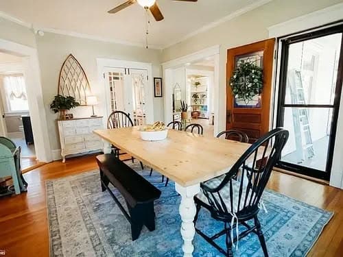 Bright dining room featuring a wooden table, black chairs, and decorative rug. Cozy and inviting space.