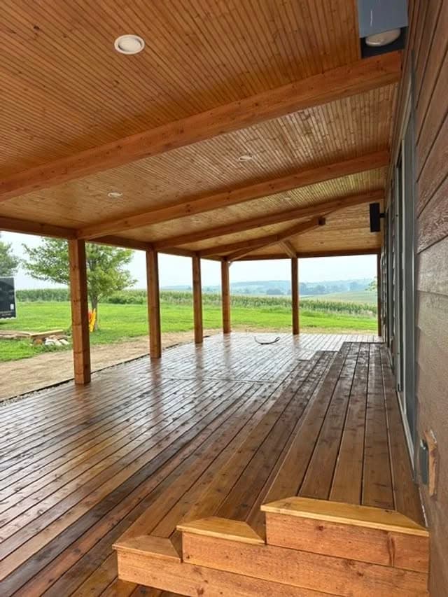 Spacious wooden deck overlooking lush vineyards and rolling hills in bright daylight.
