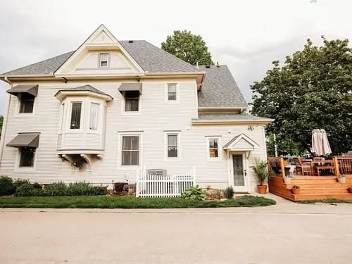 Victorian-style house with a porch, landscaped yard, and outdoor dining area.