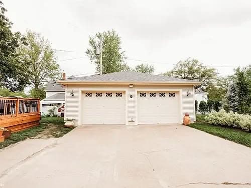 Modern two-car garage with paneled doors and a well-maintained driveway and garden.