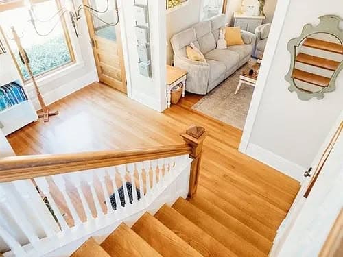 Bright entryway with hardwood stairs leading to a cozy living room and stylish decor.