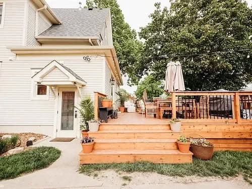 Modern home exterior featuring a wooden deck, patio, and landscaped yard. Ideal for outdoor living.
