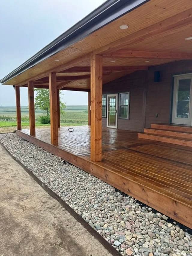 Modern home exterior featuring a wooden porch with stone landscaping and expansive views.