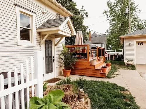 Charming home exterior with wooden deck, potted plants, and inviting entrance.