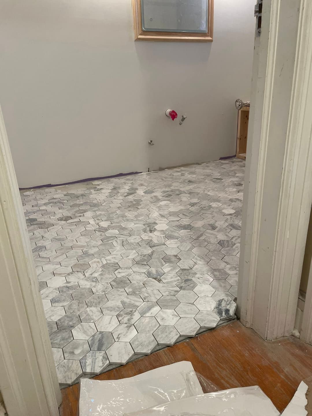 Newly tiled bathroom floor featuring hexagon marble tiles. Renovation project in progress.