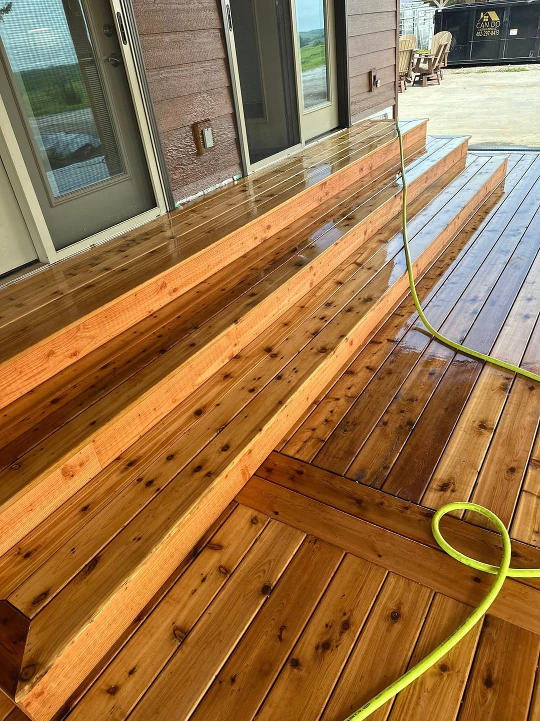 Wooden deck with freshly polished steps and a green hose along the side for maintenance.