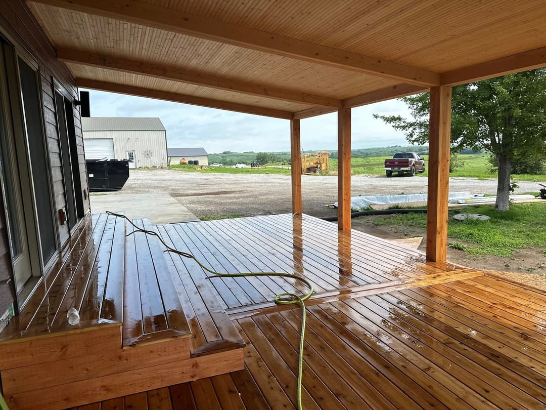 Newly finished wooden deck with a clean surface, featuring a covered porch and outdoor view.
