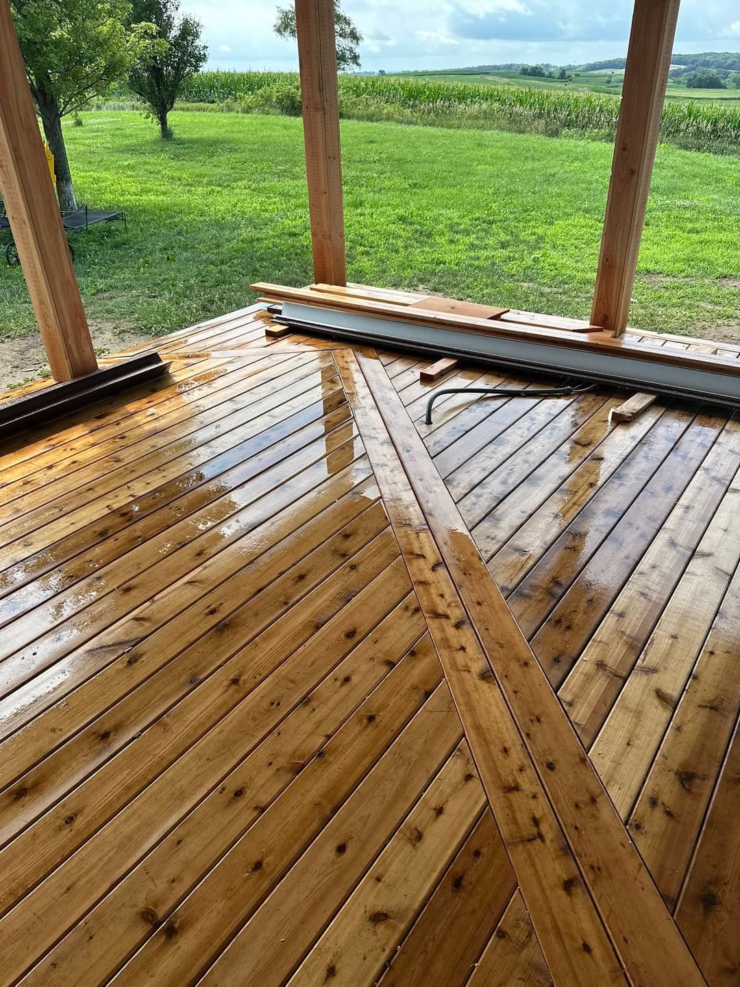 Polished wooden deck with diagonal planks overlooking lush green fields.