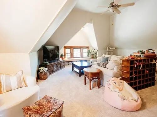Cozy attic living room with plush seating, large windows, and a wooden wine rack.
