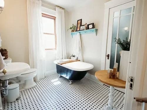 Modern bathroom featuring a vintage freestanding tub, patterned tile floor, and natural lighting.