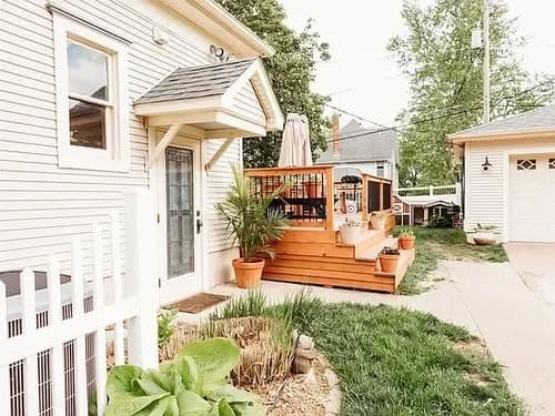 Charming home exterior with wooden deck, plants, and welcoming entryway.
