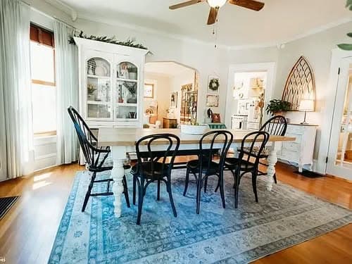 Bright dining room featuring a large wooden table, black chairs, and elegant decor.