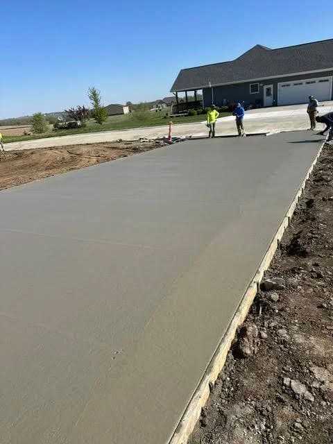 Concrete slab being poured in a residential area with construction workers on site.