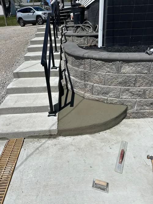Concrete stairs and curved patio with construction tools during installation process.