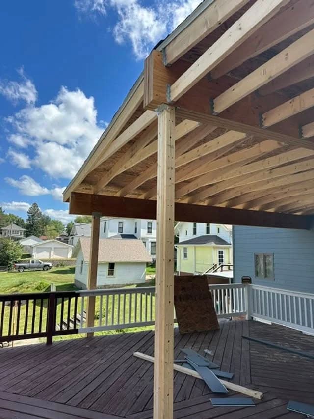 Newly constructed wooden deck with open beams and clear blue sky in the background.
