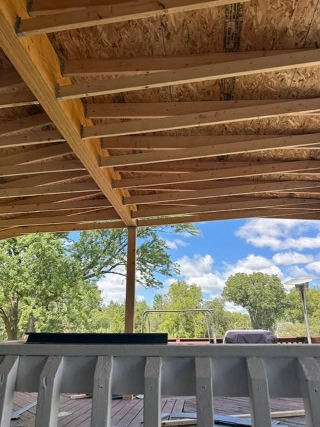 View of an unfinished deck with exposed beams and blue skies in the background.