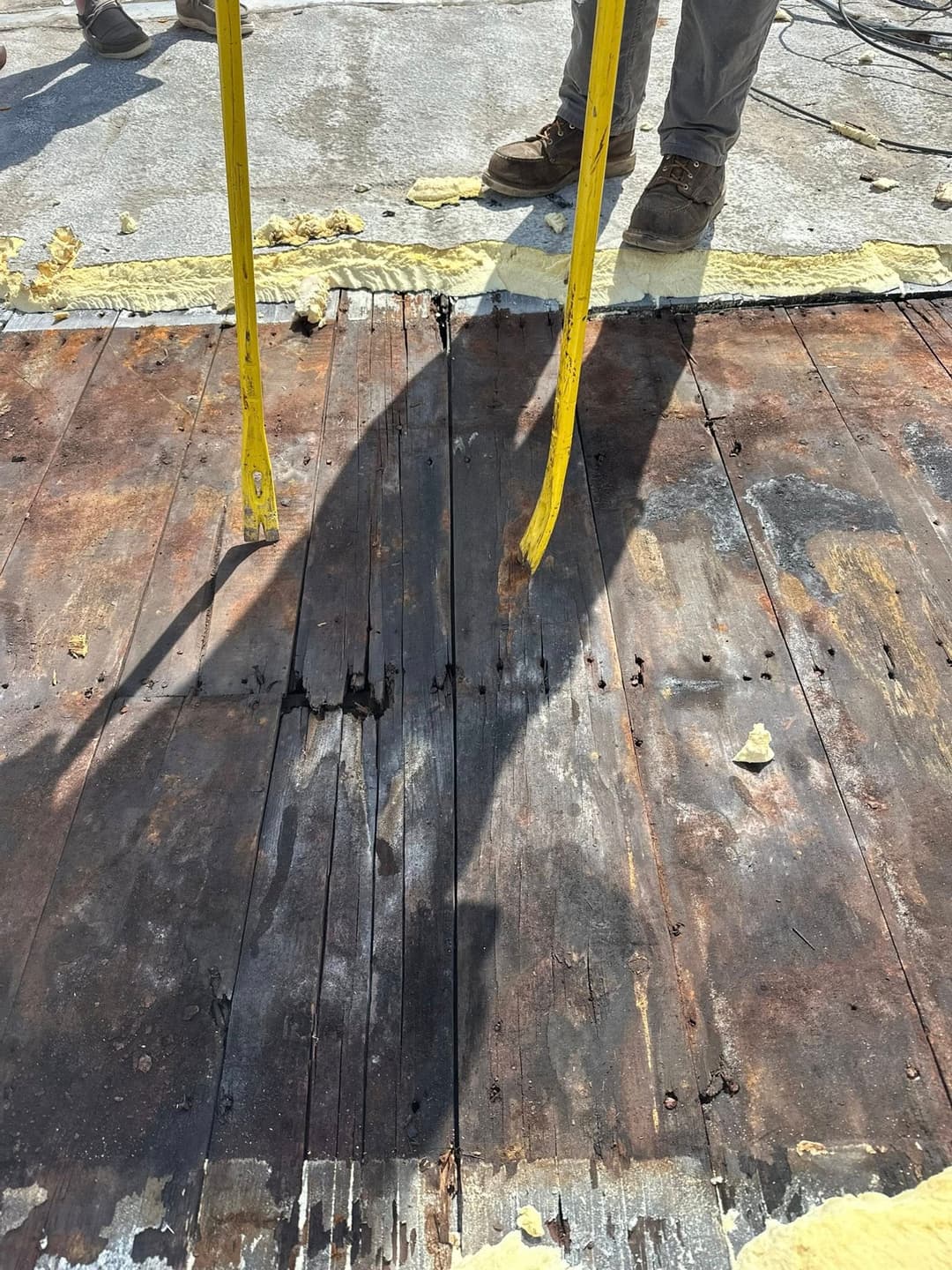 Roof repair showing rot on wooden boards with a tape measure on site for measurement.