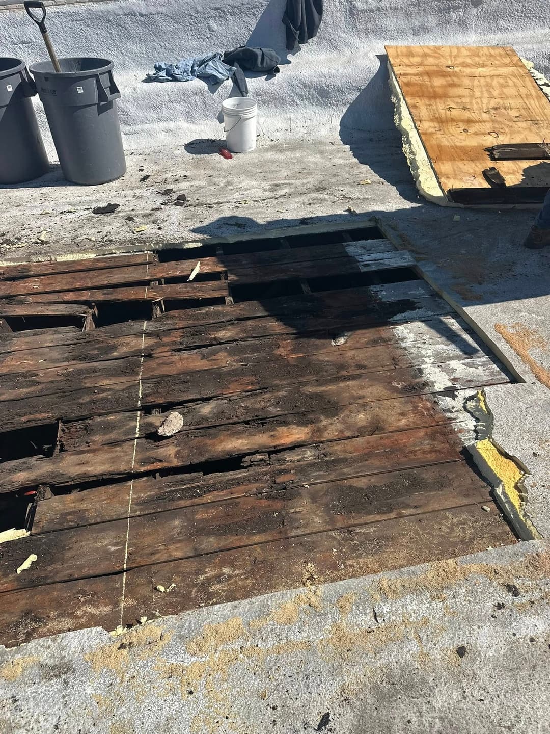 Damaged wooden floorboards exposed during renovation, with tools and debris nearby.