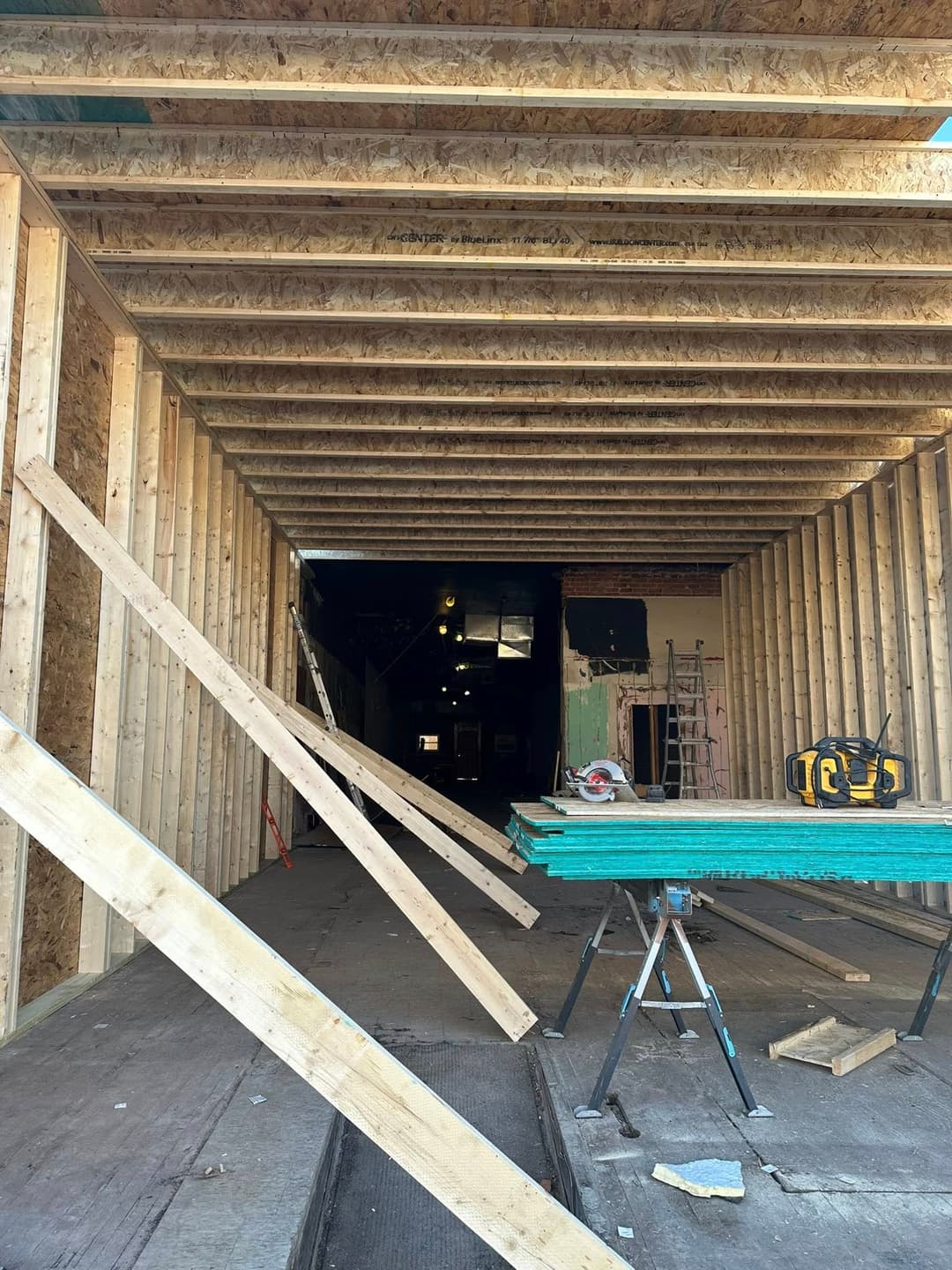 View of an under-construction interior with wooden beams, tools, and scaffolding.