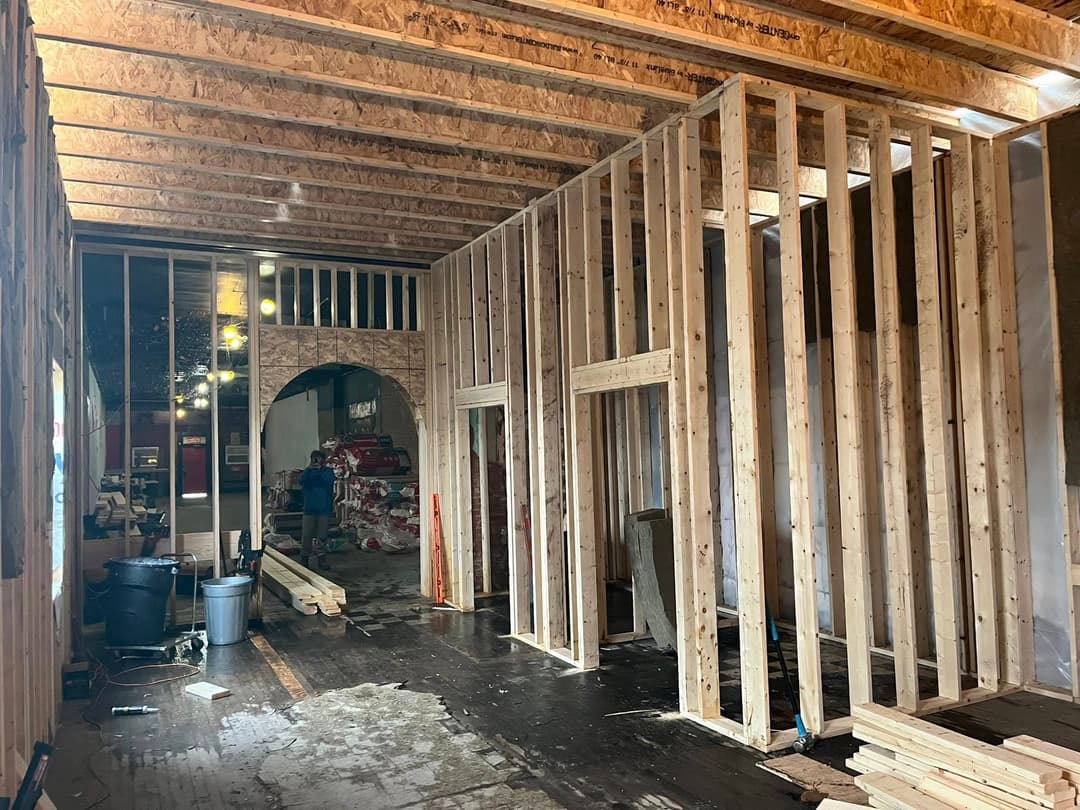 Interior construction with wooden framing, open space, and unfinished flooring.