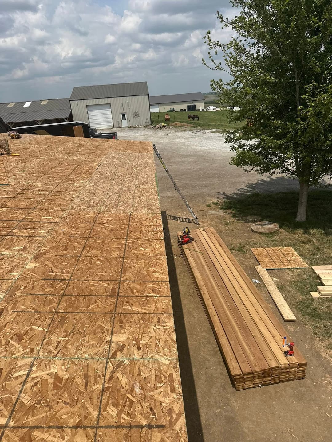 Construction site with wooden planks and newly laid OSB sheathing under a cloudy sky.