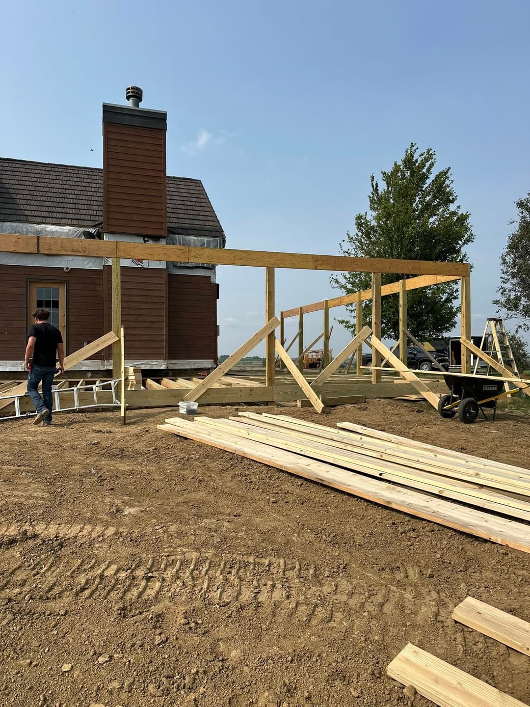 Construction site featuring wooden frame structure and building materials near a house.