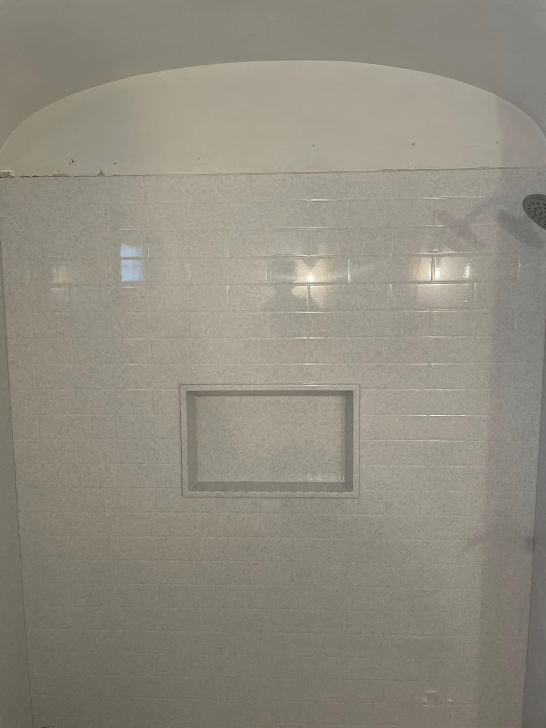 Modern shower with white tile walls and built-in niche for storage.