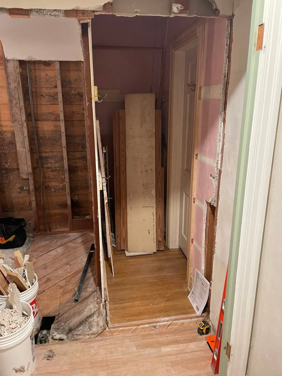 Renovation in progress: open doorway revealing unfinished walls and wooden flooring.