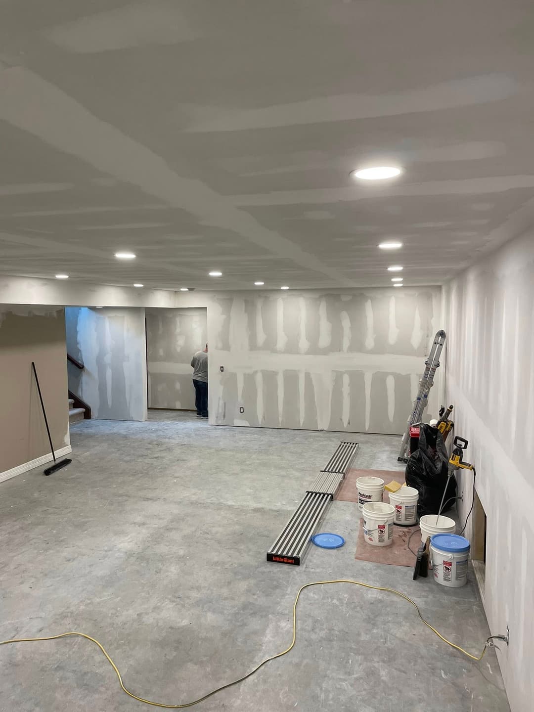 Newly drywall-finished basement with recessed lighting and painting supplies.