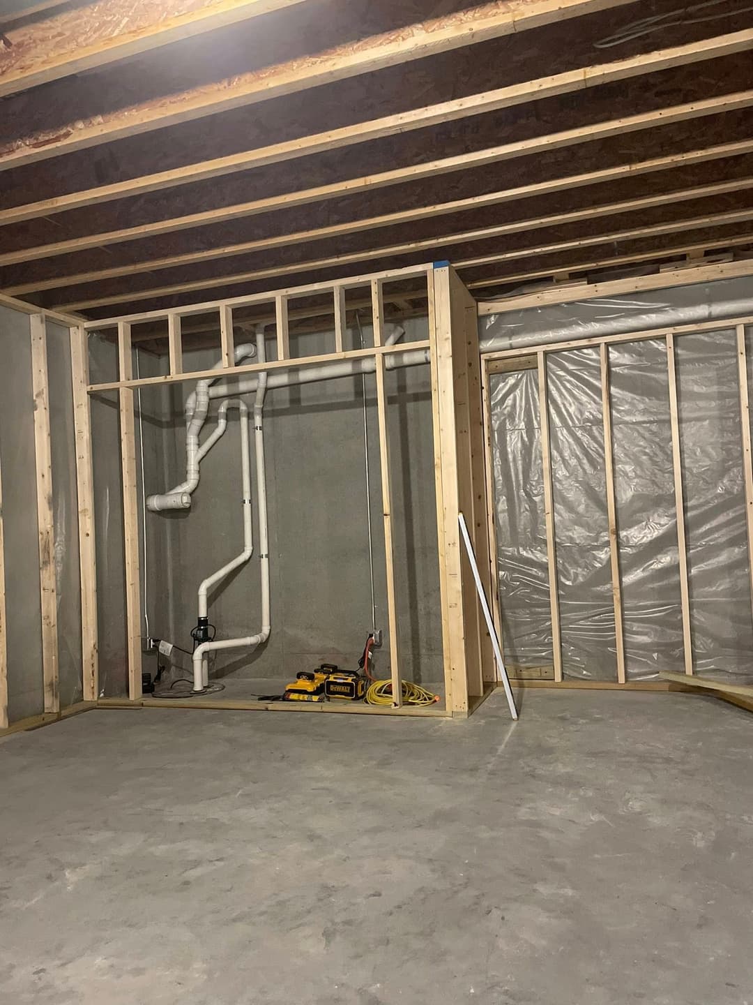 Basement construction with framed walls and plumbing, showcasing unfinished interior.