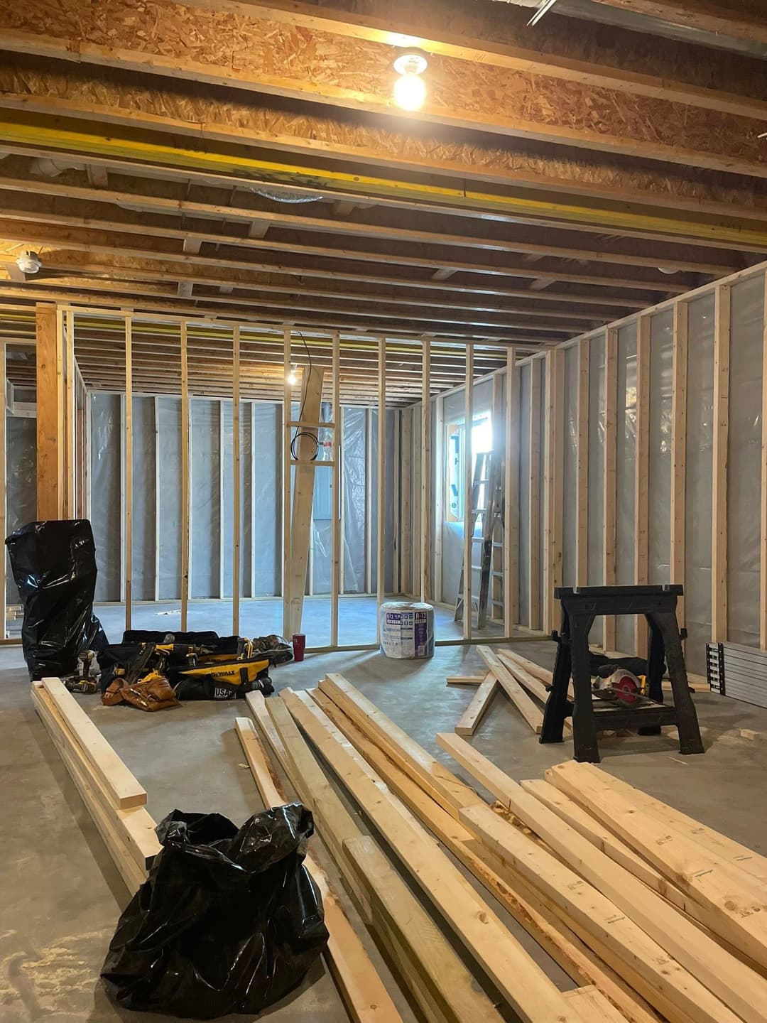 Framed interior of a basement under construction with tools and lumber.