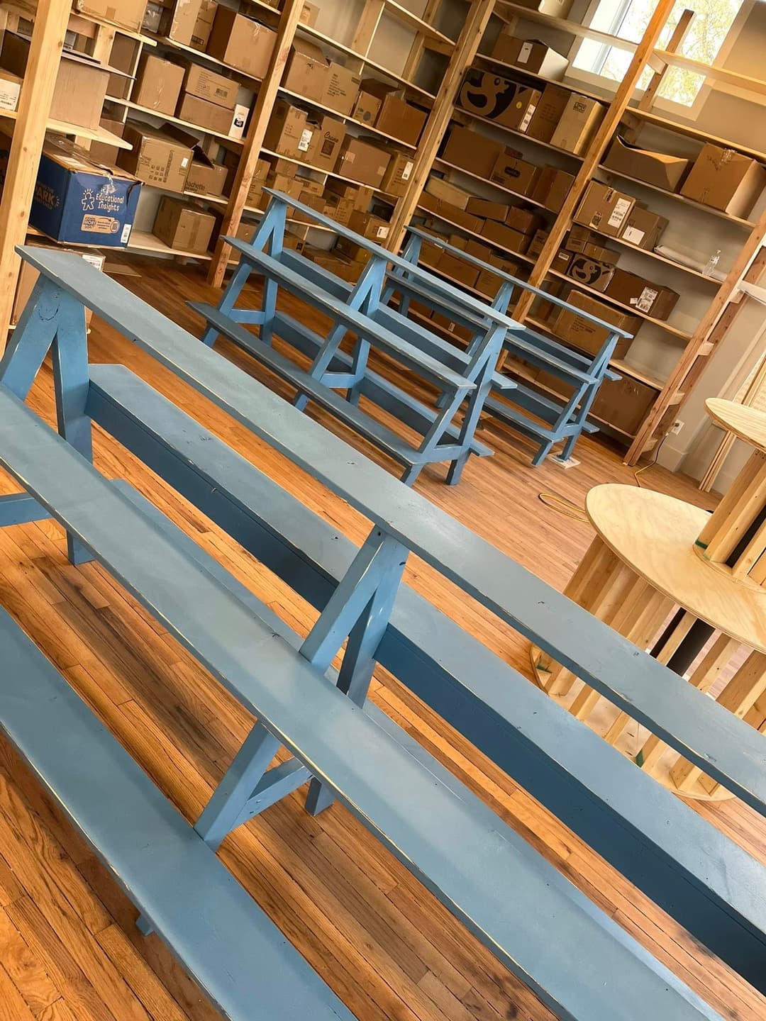 Empty blue wooden benches in a spacious room with shelves and boxes.