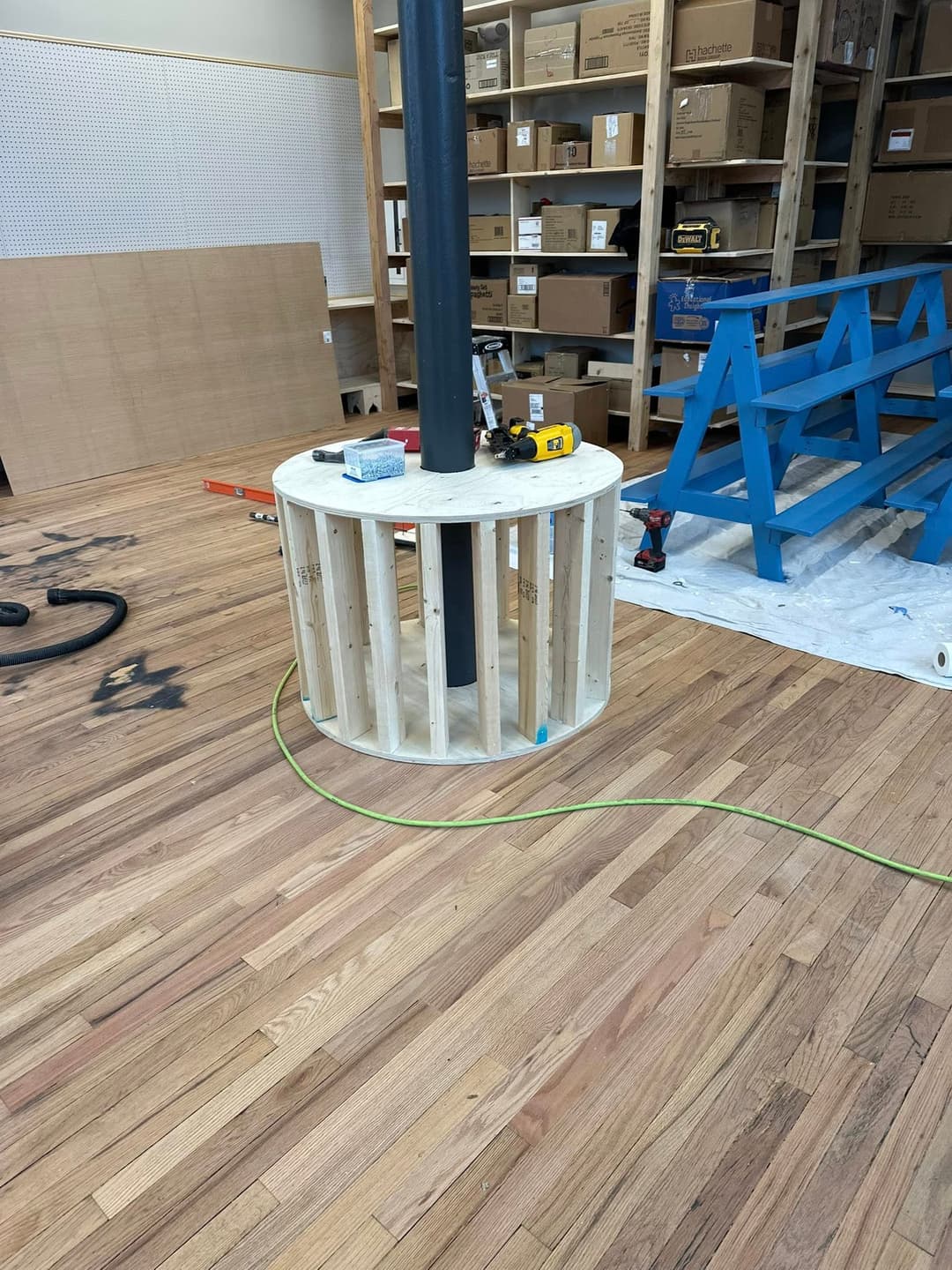 Wooden base construction around a central pillar in a workshop setting with tools nearby.